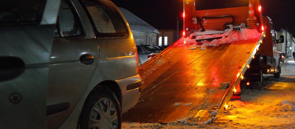 Loading a car on a tow truck lighted platform close up side view